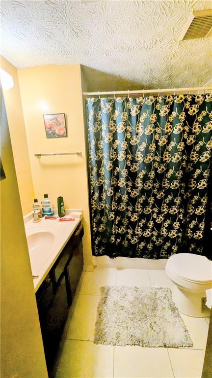 4256 Village Square Ln, Stone Mountain, GA 30083 - bathroom with tile patterned flooring, a shower with curtain, toilet, and vanity