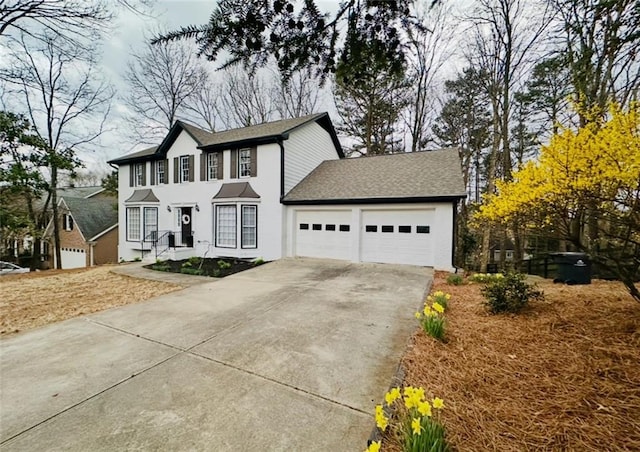 colonial house featuring a garage, driveway, and roof with shingles