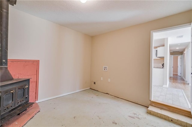 unfurnished living room with unfinished concrete floors and a wood stove