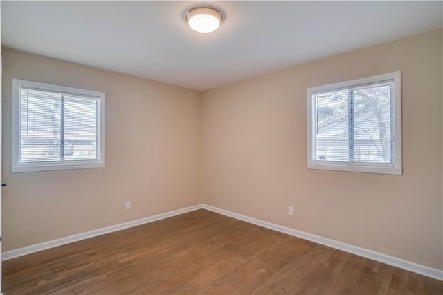 unfurnished room with baseboards, wood finished floors, and plenty of natural light