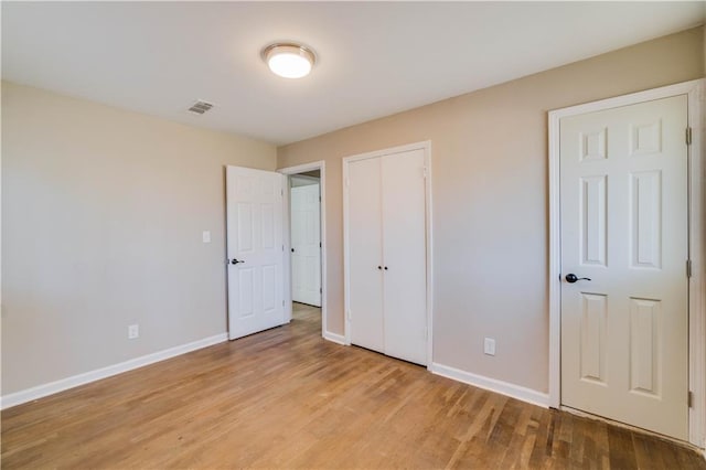 unfurnished bedroom with light wood finished floors, a closet, visible vents, and baseboards