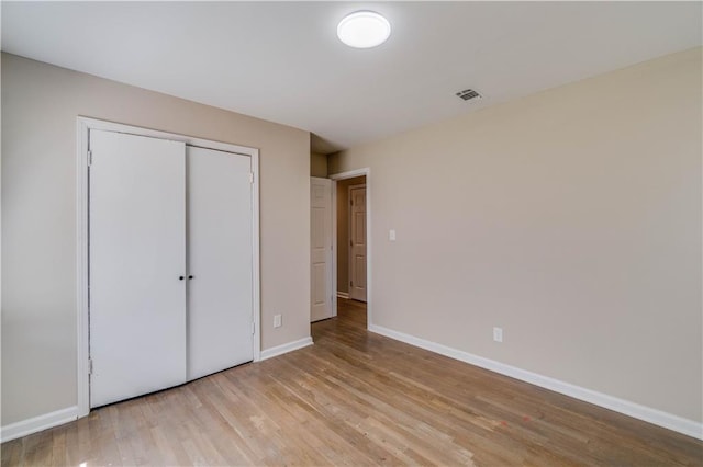 unfurnished bedroom with baseboards, visible vents, light wood-type flooring, and a closet