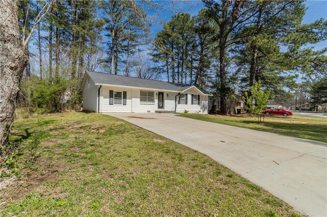 ranch-style home with concrete driveway and a front lawn