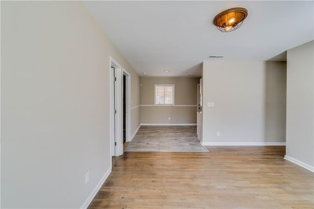 unfurnished room featuring baseboards, visible vents, and light wood-type flooring