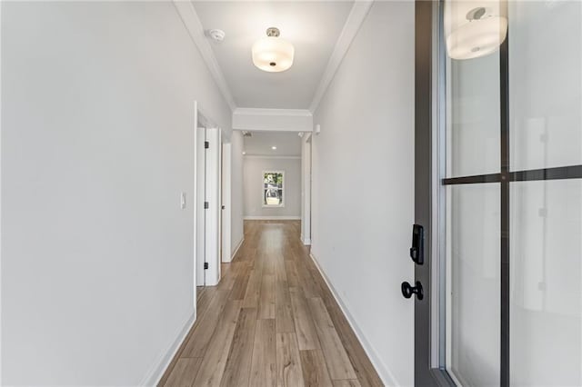 corridor with ornamental molding and light hardwood / wood-style floors