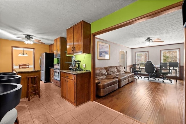 kitchen with stainless steel appliances, open floor plan, brown cabinets, and a textured ceiling