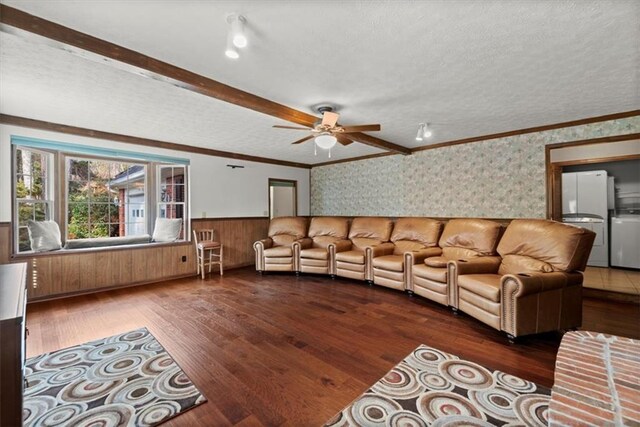 living room featuring a textured ceiling, dark wood-type flooring, ornamental molding, wainscoting, and wallpapered walls