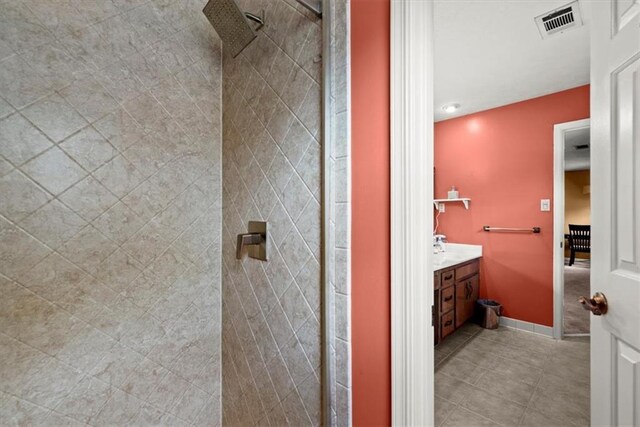 bathroom with tiled shower, tile patterned flooring, vanity, and visible vents