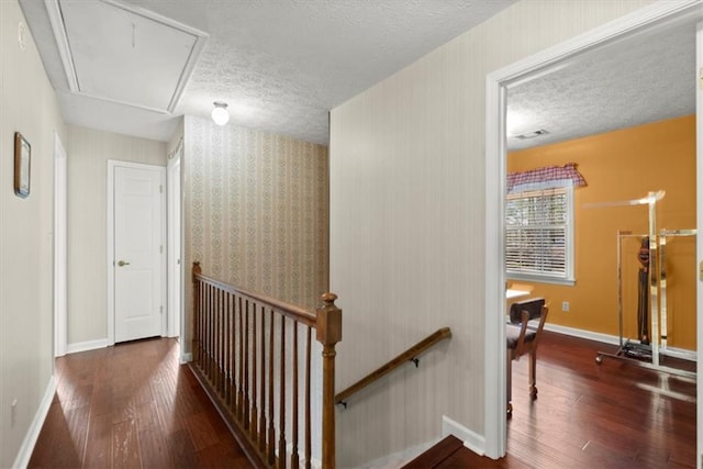 corridor featuring attic access, baseboards, dark wood-type flooring, and an upstairs landing