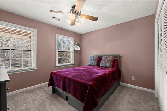 bedroom with visible vents, ceiling fan, light carpet, and baseboards