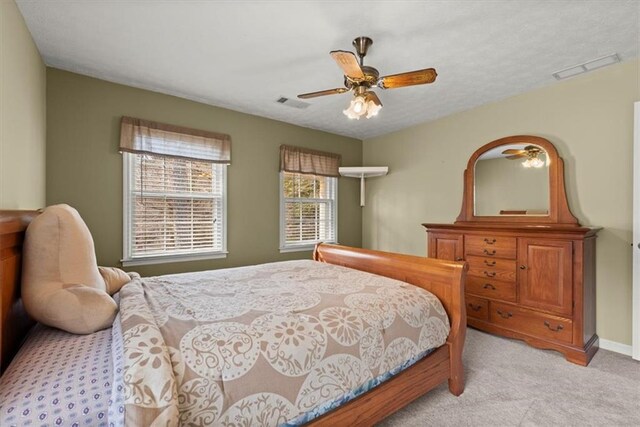 bedroom featuring a ceiling fan, visible vents, light carpet, and baseboards