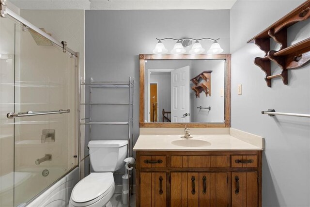 bathroom featuring toilet, bath / shower combo with glass door, and vanity