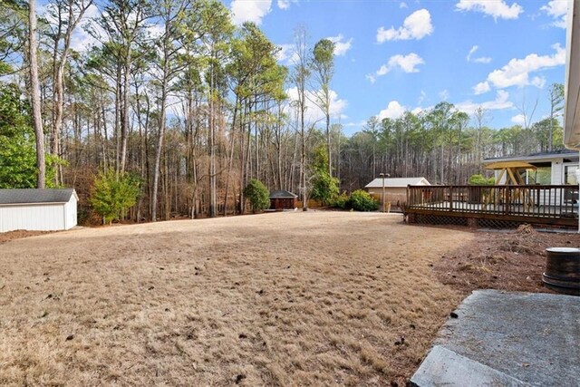 view of yard featuring a shed, a deck, and an outbuilding