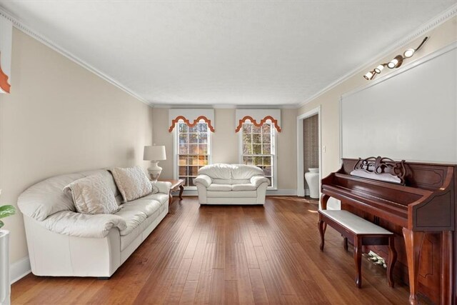living area featuring baseboards, wood finished floors, and crown molding