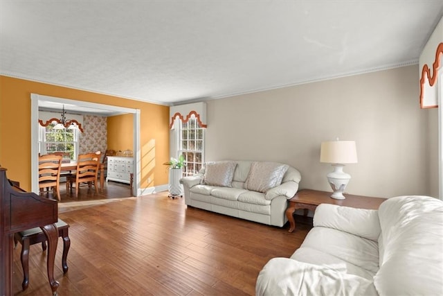 living room with a chandelier, ornamental molding, baseboards, and wood finished floors