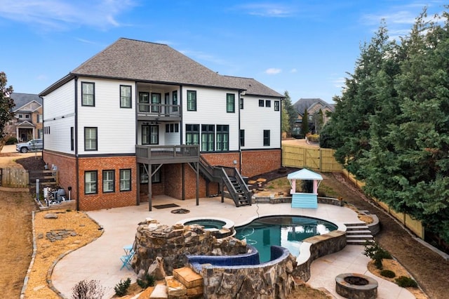 rear view of house with an outdoor fire pit, a patio, a balcony, stairs, and brick siding