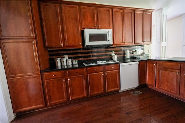 5452 Old Dalton Rd NE, Calhoun, GA 30701 - kitchen with white appliances, dark wood-type flooring, dark countertops, backsplash, and brown cabinets
