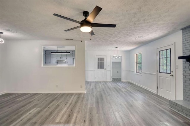 2931 Randolph Ct, Conyers, GA 30012 - unfurnished living room with wood finished floors, a textured ceiling, a ceiling fan, baseboards, and a brick fireplace