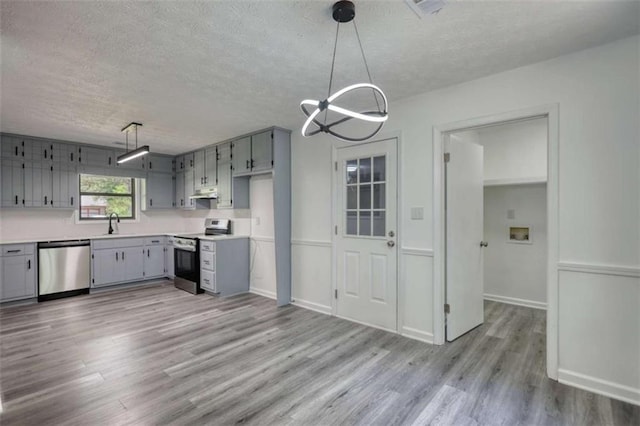 2931 Randolph Ct, Conyers, GA 30012 - kitchen with appliances with stainless steel finishes, gray cabinetry, a textured ceiling, light wood-type flooring, and under cabinet range hood