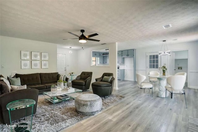 2931 Randolph Ct, Conyers, GA 30012 - living room with wood finished floors, a chandelier, a textured ceiling, ceiling fan, and baseboards