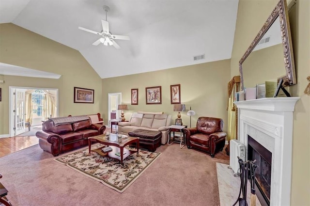 living area with carpet, a fireplace with flush hearth, a ceiling fan, and visible vents