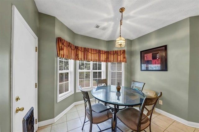 dining area with light tile patterned floors, visible vents, a textured ceiling, and baseboards