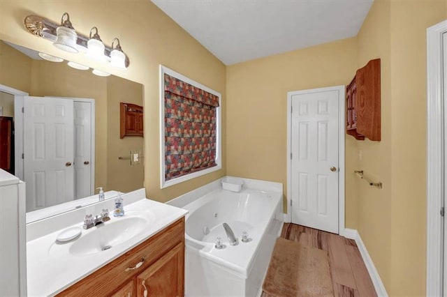 bathroom with wood finished floors, vanity, baseboards, and a whirlpool tub