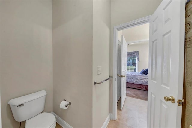 ensuite bathroom featuring toilet, baseboards, and connected bathroom