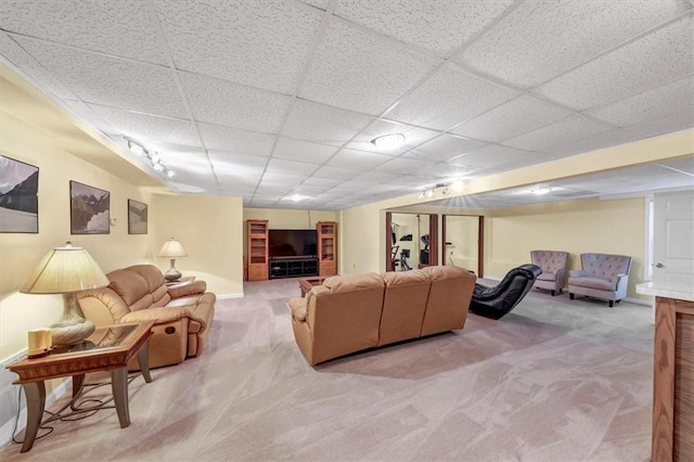 living area featuring light colored carpet, baseboards, and a drop ceiling