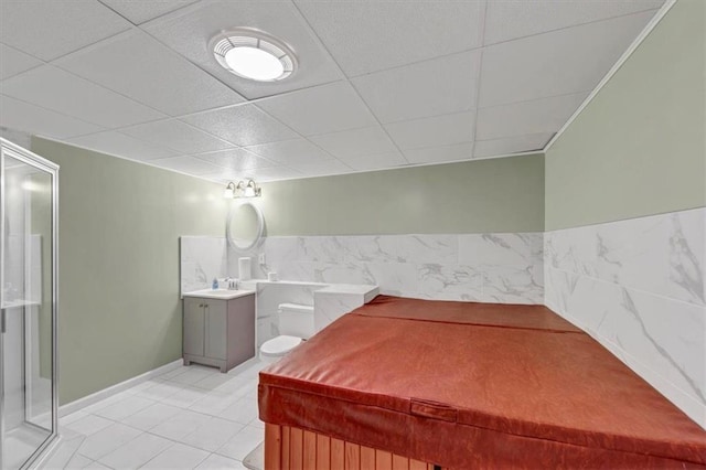 bathroom with tile patterned flooring, a drop ceiling, a stall shower, and vanity