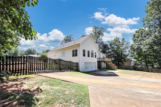 view of side of property featuring stairway, driveway, an attached garage, and fence