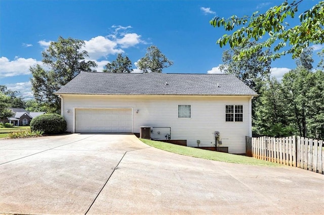 view of side of property featuring a garage, cooling unit, driveway, and fence