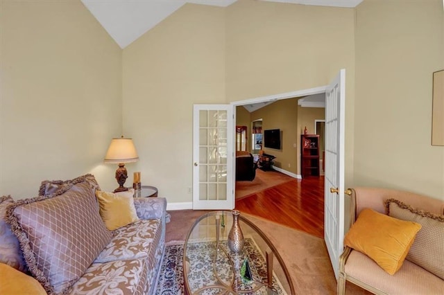 living area with carpet, wood finished floors, baseboards, high vaulted ceiling, and french doors