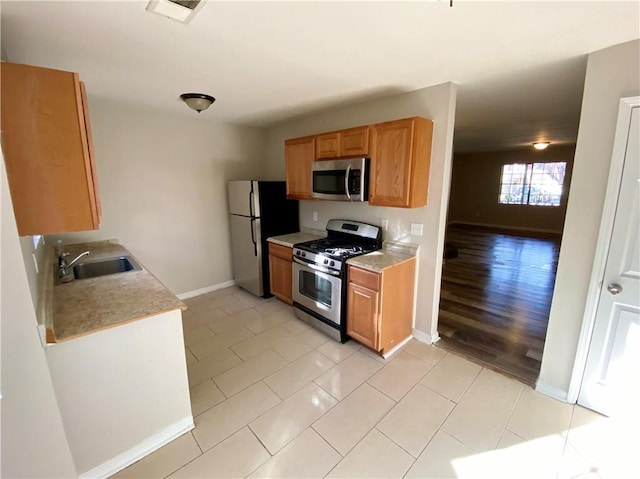 kitchen with appliances with stainless steel finishes, sink, and light tile patterned floors