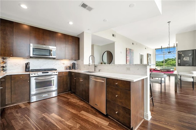 905 Juniper St NE Unit 805, Atlanta, GA 30309 - kitchen featuring appliances with stainless steel finishes, a peninsula, dark wood finished floors, backsplash, and dark brown cabinets