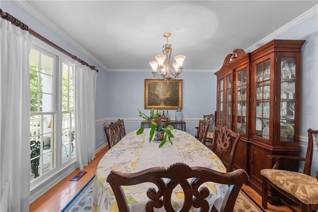 dining space featuring crown molding, light hardwood / wood-style floors, and a notable chandelier