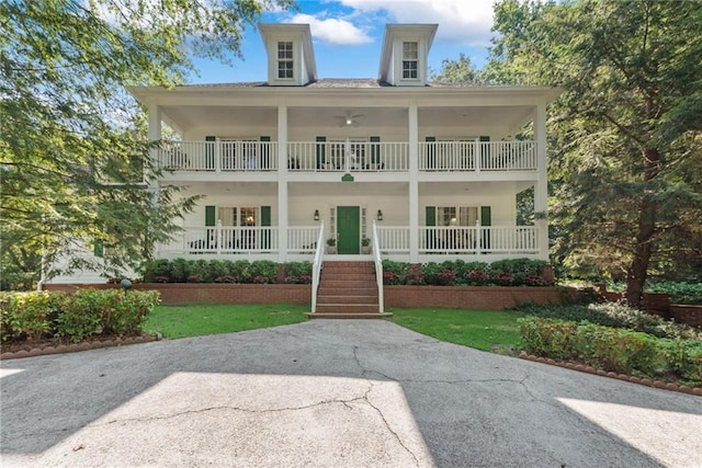 view of front of home with covered porch, a balcony, and a front yard