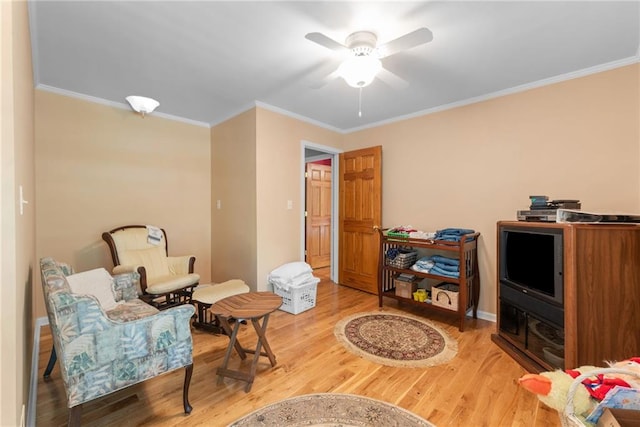 living area featuring ceiling fan, wood-type flooring, and ornamental molding