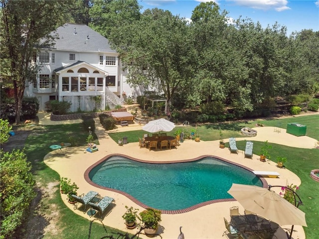 view of swimming pool with a sunroom, a diving board, a yard, and a patio