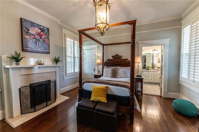 tiled bedroom with a tile fireplace, ensuite bathroom, a chandelier, and ornamental molding