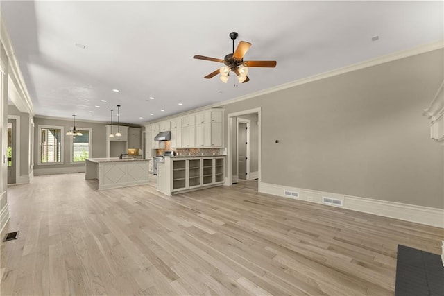 unfurnished living room with baseboards, visible vents, ornamental molding, and ceiling fan with notable chandelier