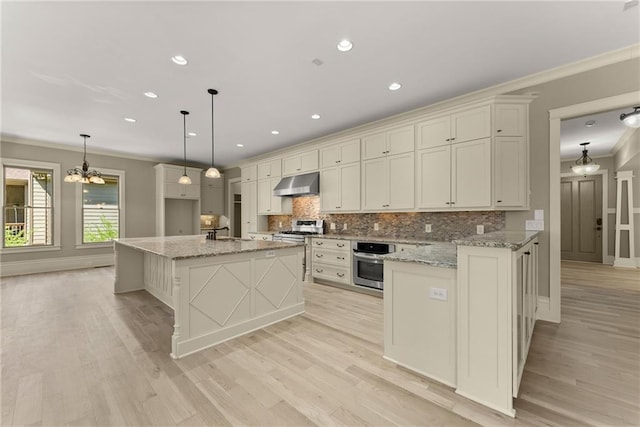 kitchen featuring crown molding, a sink, a chandelier, stainless steel oven, and under cabinet range hood