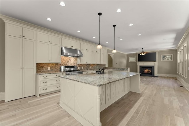 kitchen with ceiling fan, range with two ovens, tasteful backsplash, light wood finished floors, and under cabinet range hood
