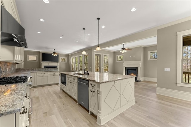 kitchen with stainless steel dishwasher, open floor plan, ceiling fan, and a lit fireplace