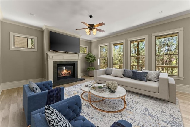 living area featuring baseboards, a ceiling fan, a fireplace, and light wood-type flooring