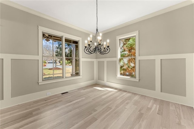 unfurnished dining area featuring a wealth of natural light, ornamental molding, a notable chandelier, and visible vents