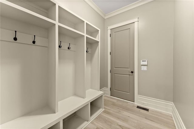mudroom with baseboards, ornamental molding, light wood-style flooring, and visible vents