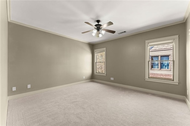 empty room featuring crown molding, light carpet, a ceiling fan, and visible vents