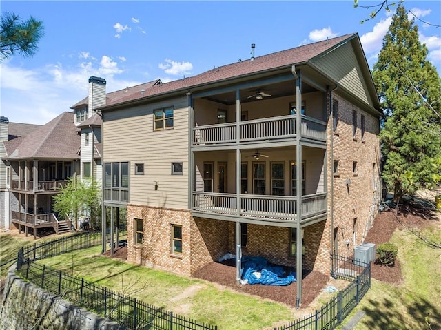 rear view of property featuring brick siding, a ceiling fan, a fenced backyard, and a balcony