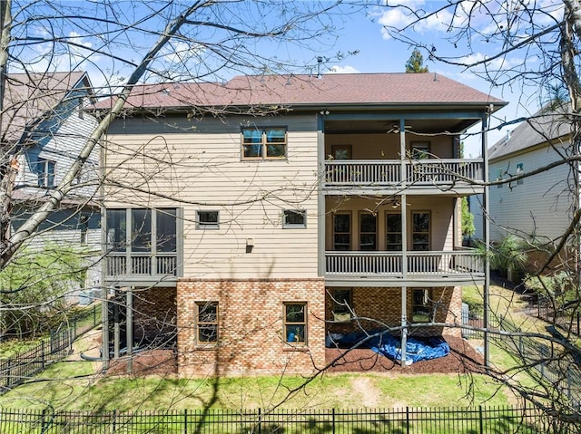 rear view of property with brick siding, a sunroom, a fenced backyard, a balcony, and a patio